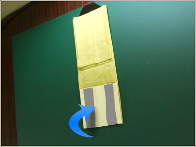 片方の袖を反対の袖の付け根部分まで折ります。